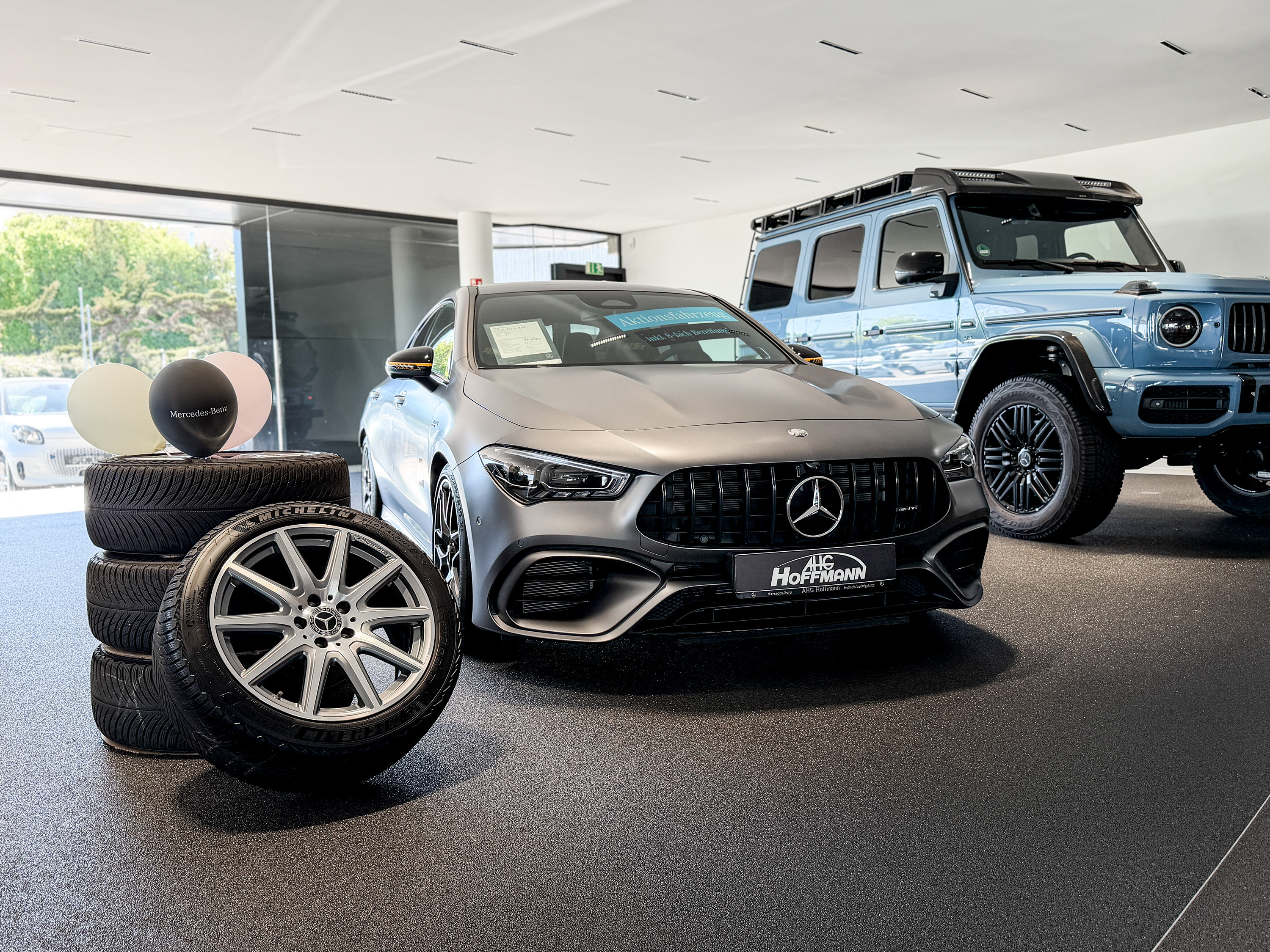 Ein grauer CLA 45 steht vor einem Stapel Reifen in einem Showroom