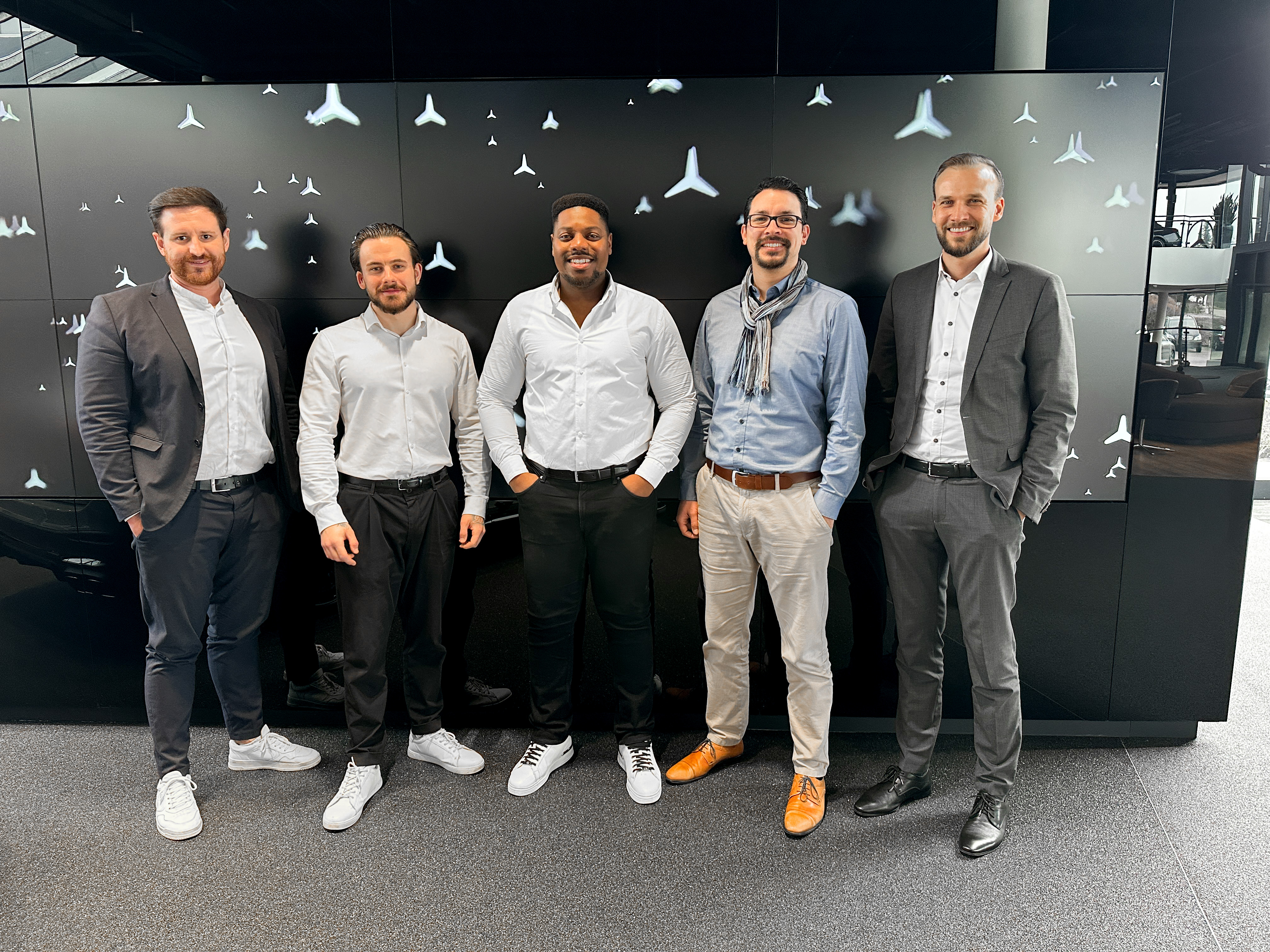 Fünf Mercedes-Benz Verkäufer stehen vor einer Sternenwand.